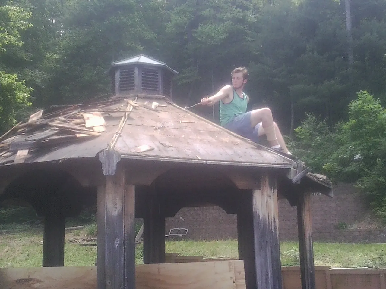 Tearing the old roof off a wooden gazebo before new shakes in Chilton