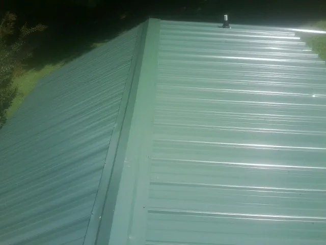 New green metal panels meeting at the ridge of a roof — Flat Roof Repair work by our crew in Chilton