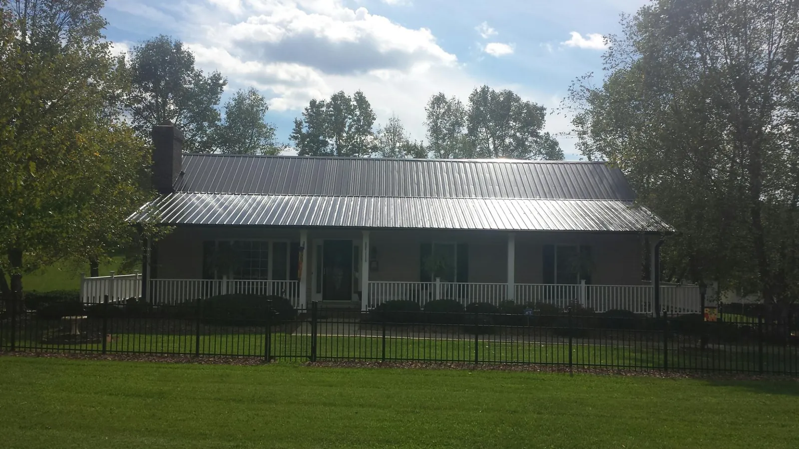 Gray metal roof on a brick ranch with a full width front porch — Gutter Guard Installation work by our crew in Chilton