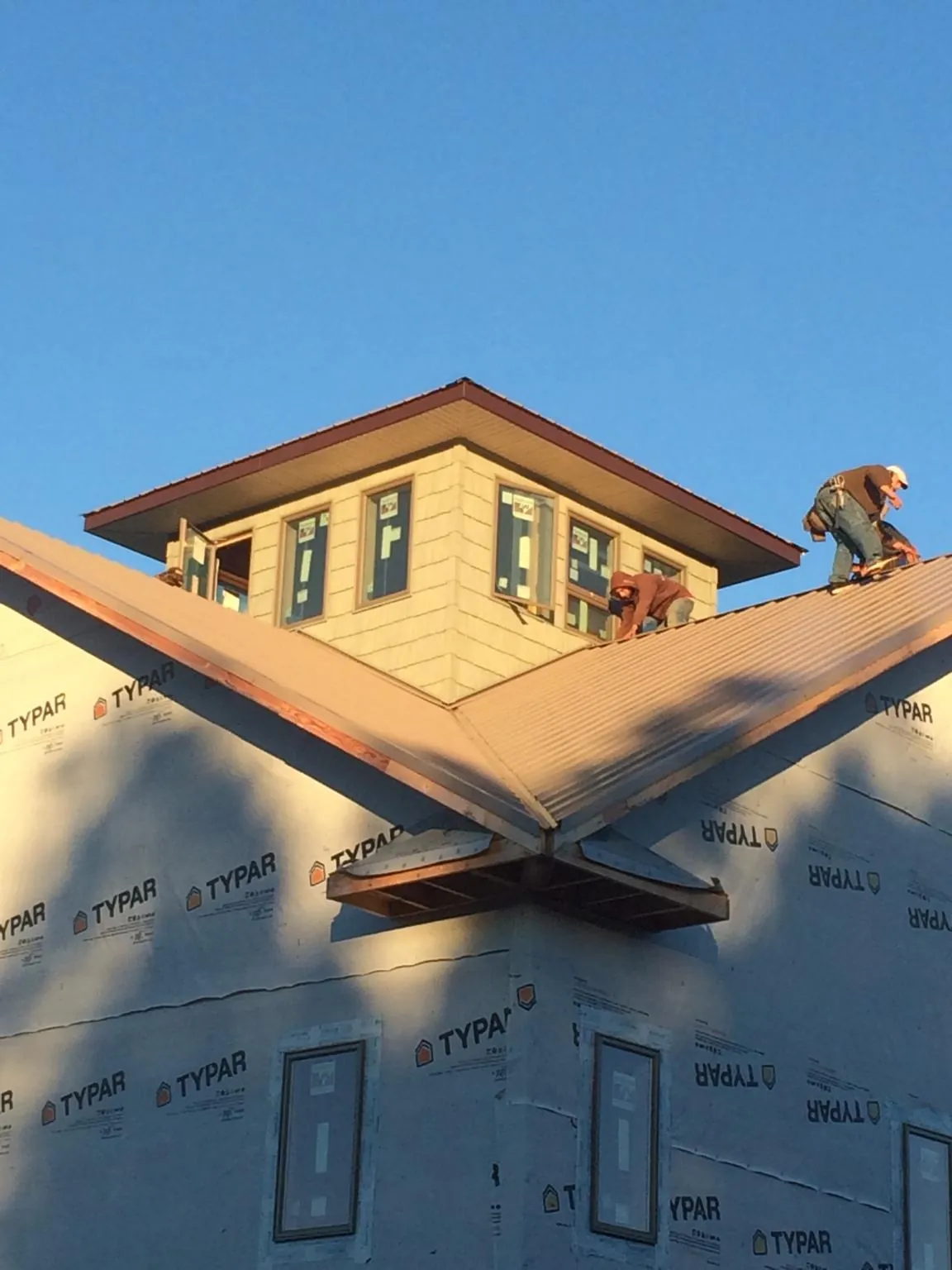 Roofers working around a rooftop cupola on a new metal roof at sunset — Roof Waterproofing in Chilton by Roofing Brothers